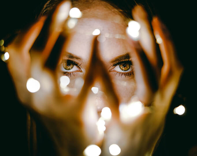 woman holding fairy lights up to her face