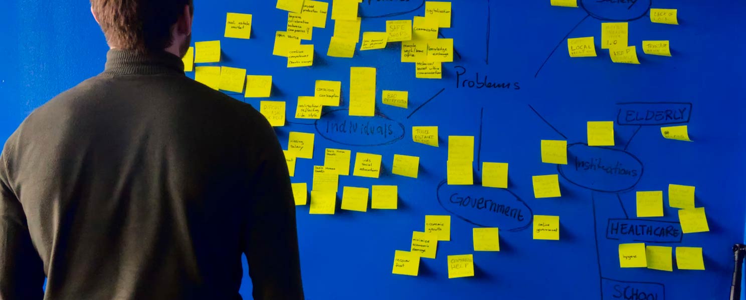 man studying mind-map covered in sticky notes and keywords