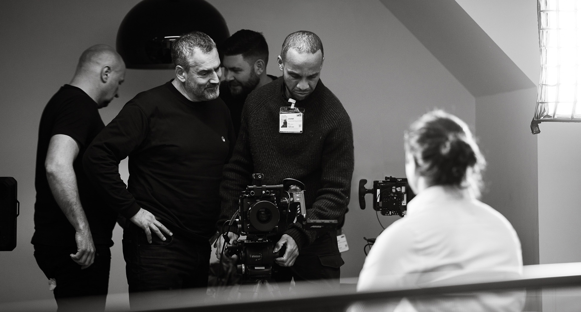 A black and white photo of a film crew gathered around a professional camera during a video production shoot.A black and white photo of a film crew gathered around a professional camera during a video production shoot.